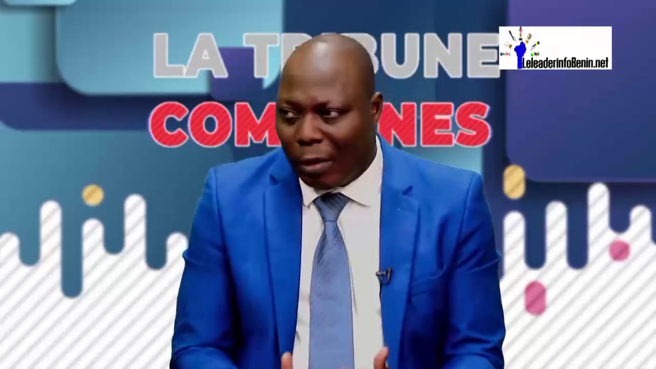 Homme en costume bleu parle dans un studio avec un panneau "LA TRIBUNE DES COMMUNES" en arrière-plan