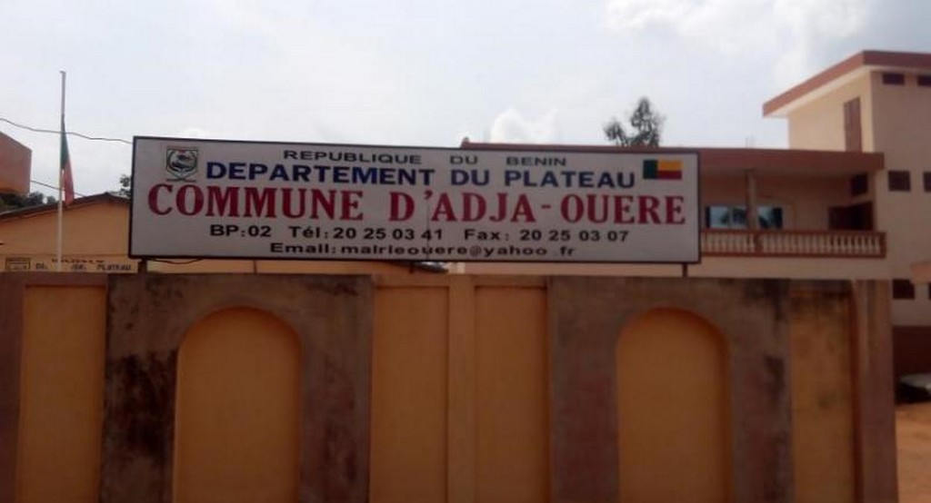 Panneau indiquant Commune d'Adja-Ouèrè dans le département du Plateau avec coordonnées de contact visible sur bâtiment jaune