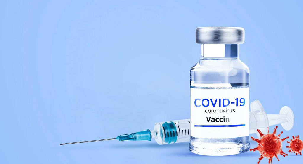 Un flacon de vaccin posé devant une seringue avec des représentations graphiques du virus sur fond bleu