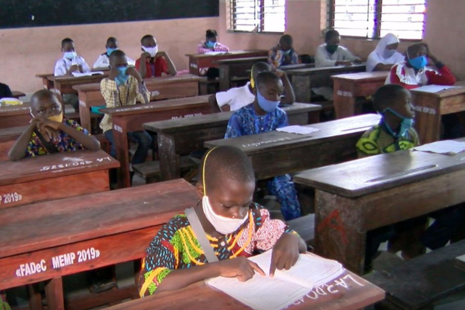 Des élèves assis par rangées respectent la distanciation et portent des masques pendant un examen en classe