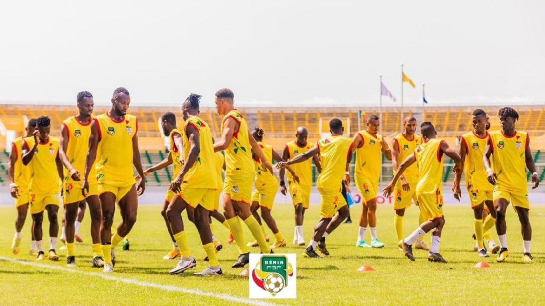 Une équipe de football en tenue jaune fait des exercices d’échauffement sur un terrain de stade en plein jour