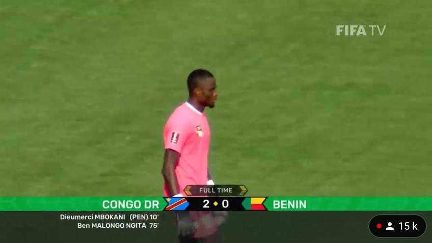 Joueur en maillot rose marchant sur le terrain avec le score Congo DR 2 Benin 0 affiché en bas de l’écran