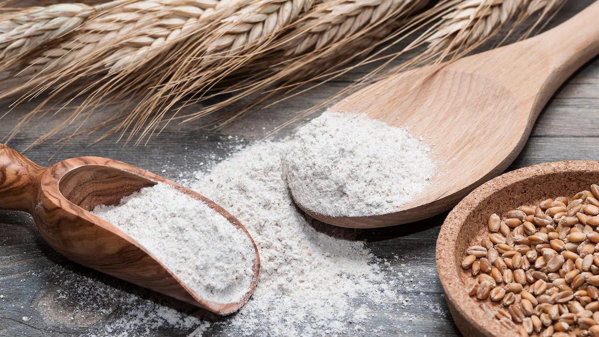 Grains de blé, farine blanche dans une cuillère en bois et une pelle sur une table en bois et épis de blé posés en arrière-plan