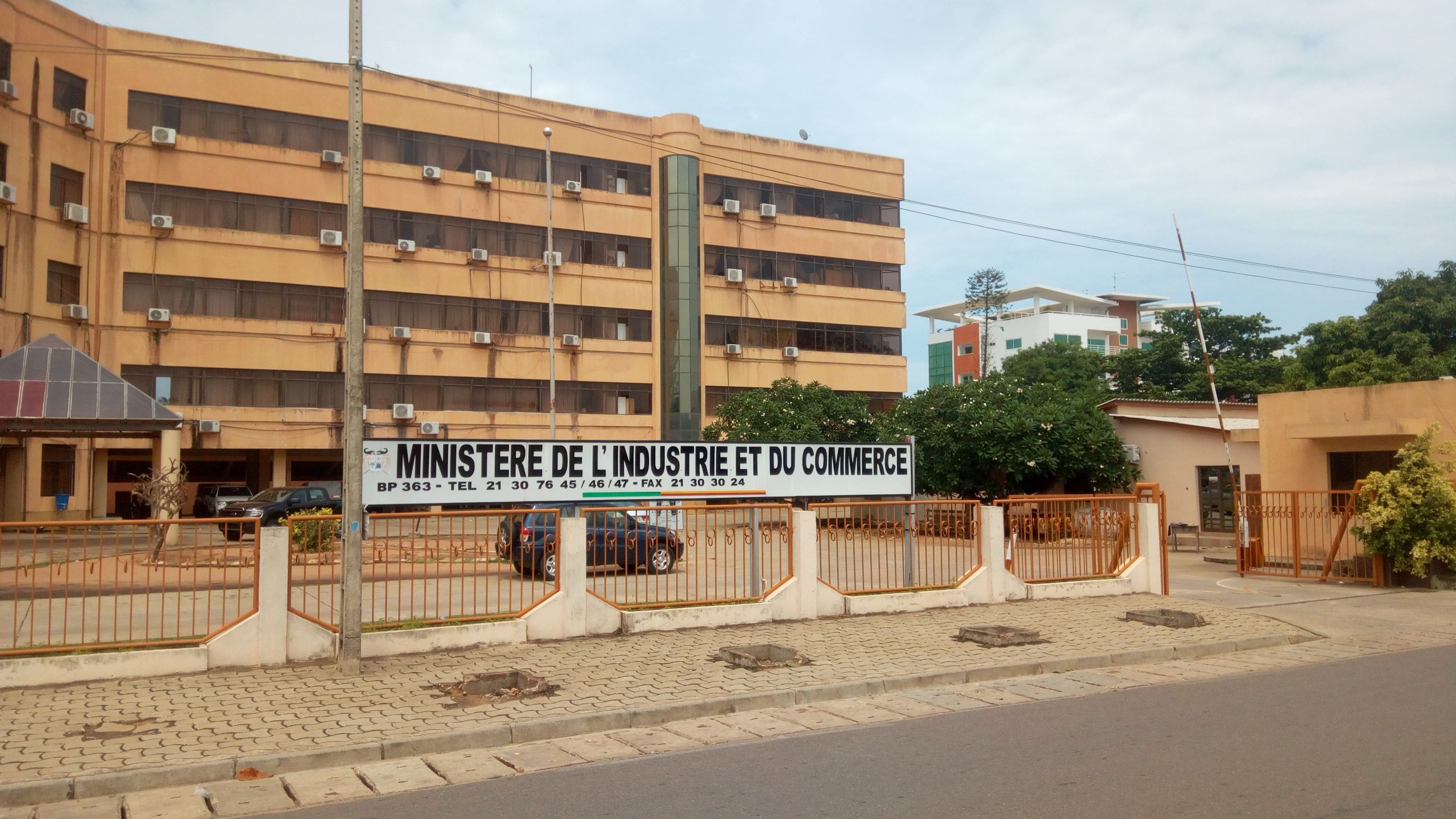 Façade d un bâtiment administratif derrière une barrière avec un panneau indiquant ministère de l industrie et du commerce