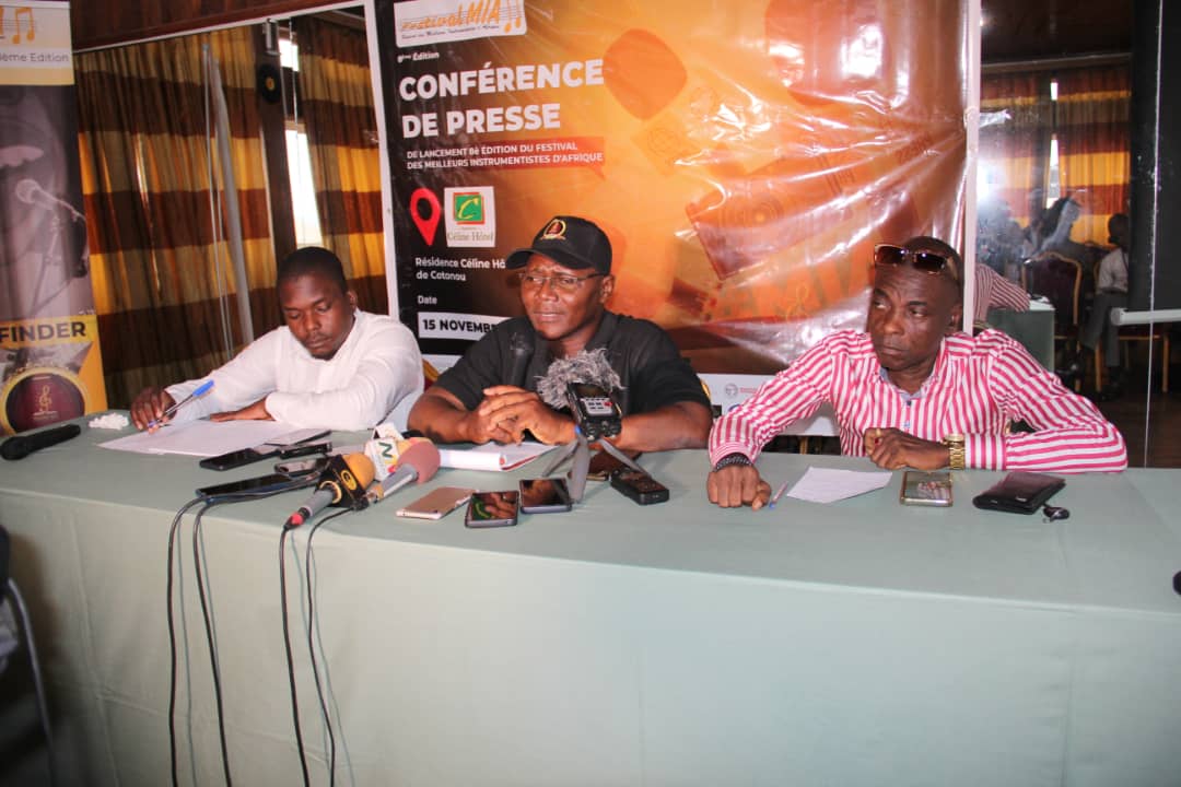 Trois hommes assis à une table avec microphones et documents lors d une conférence de presse officielle