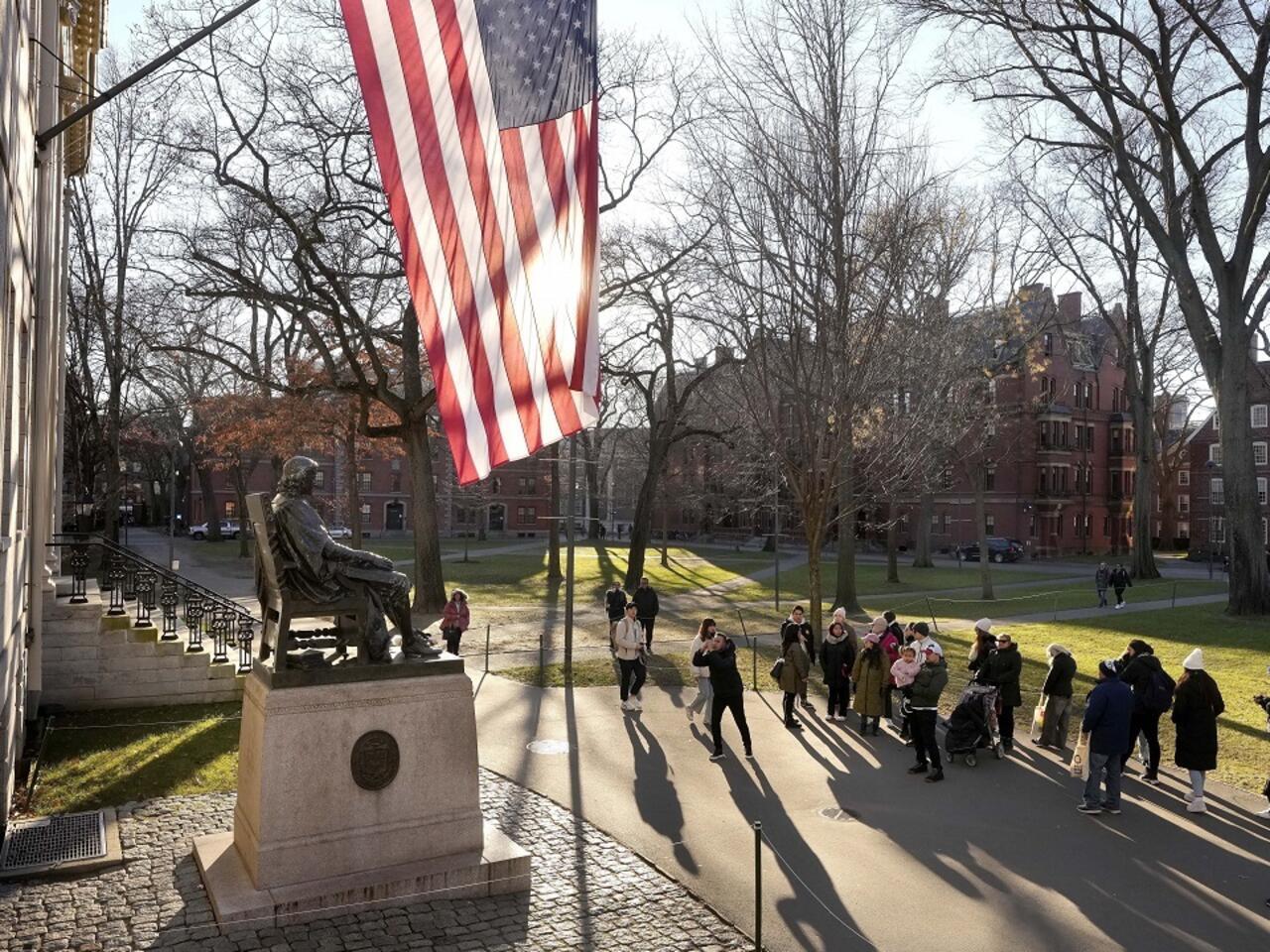 Un groupe de personnes rassemblees dans un parc avec un drapeau americain et une statue en bronze sur un socle en pierre