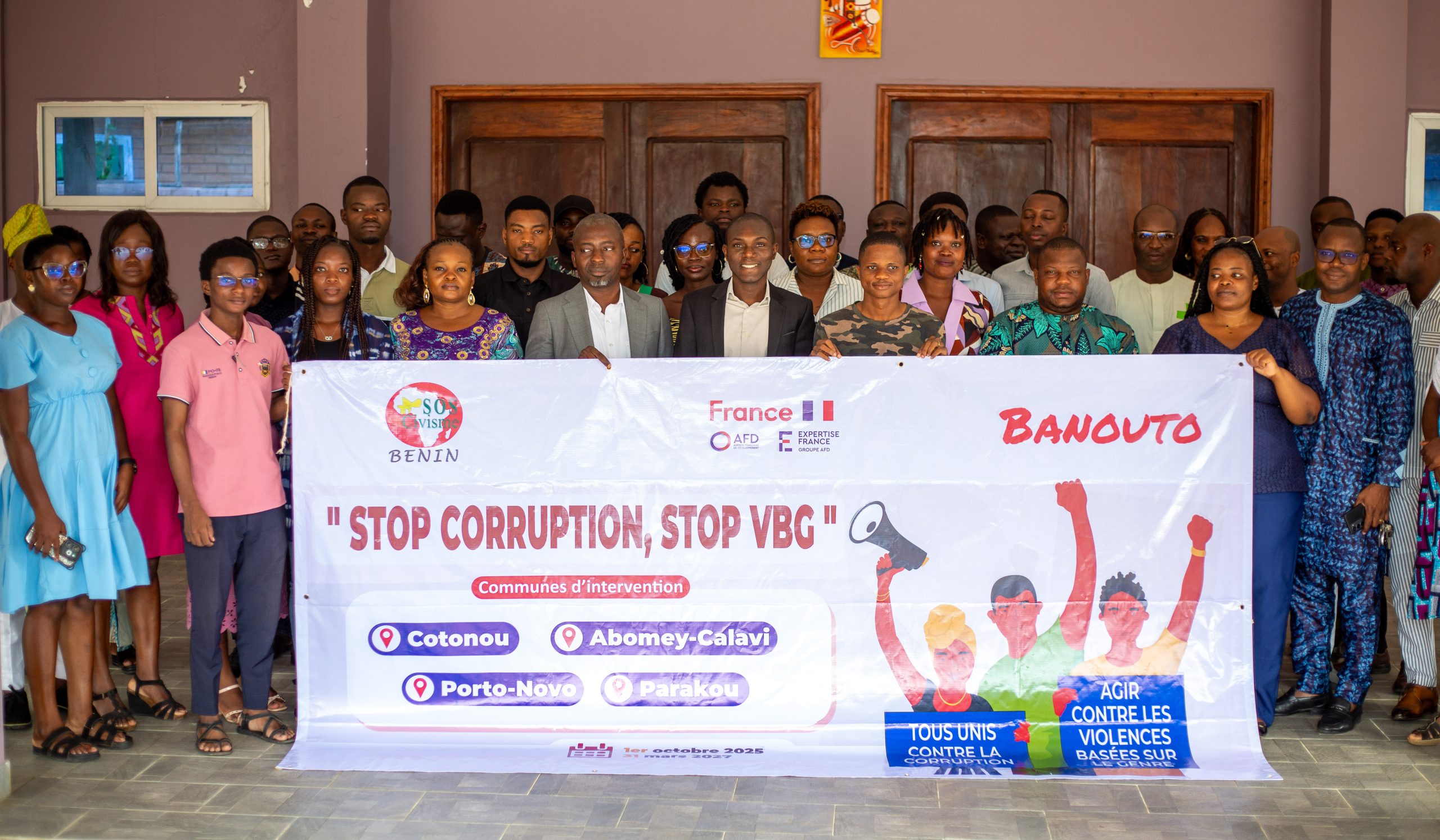 Groupe de personnes posant ensemble derrière une grande banderole sur la lutte contre la corruption et les violences basées sur le genre