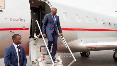 Un homme en costume descend l'escalier d'un avion privé marqué VistaJet accompagné d'un autre homme en costume sur le tarmac