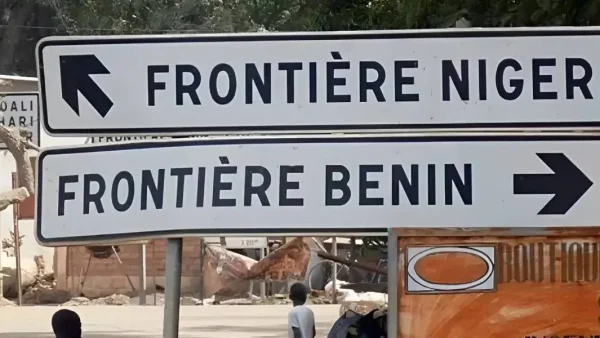 Deux panneaux de signalisation indiquent les directions des frontières avec des flèches opposées.