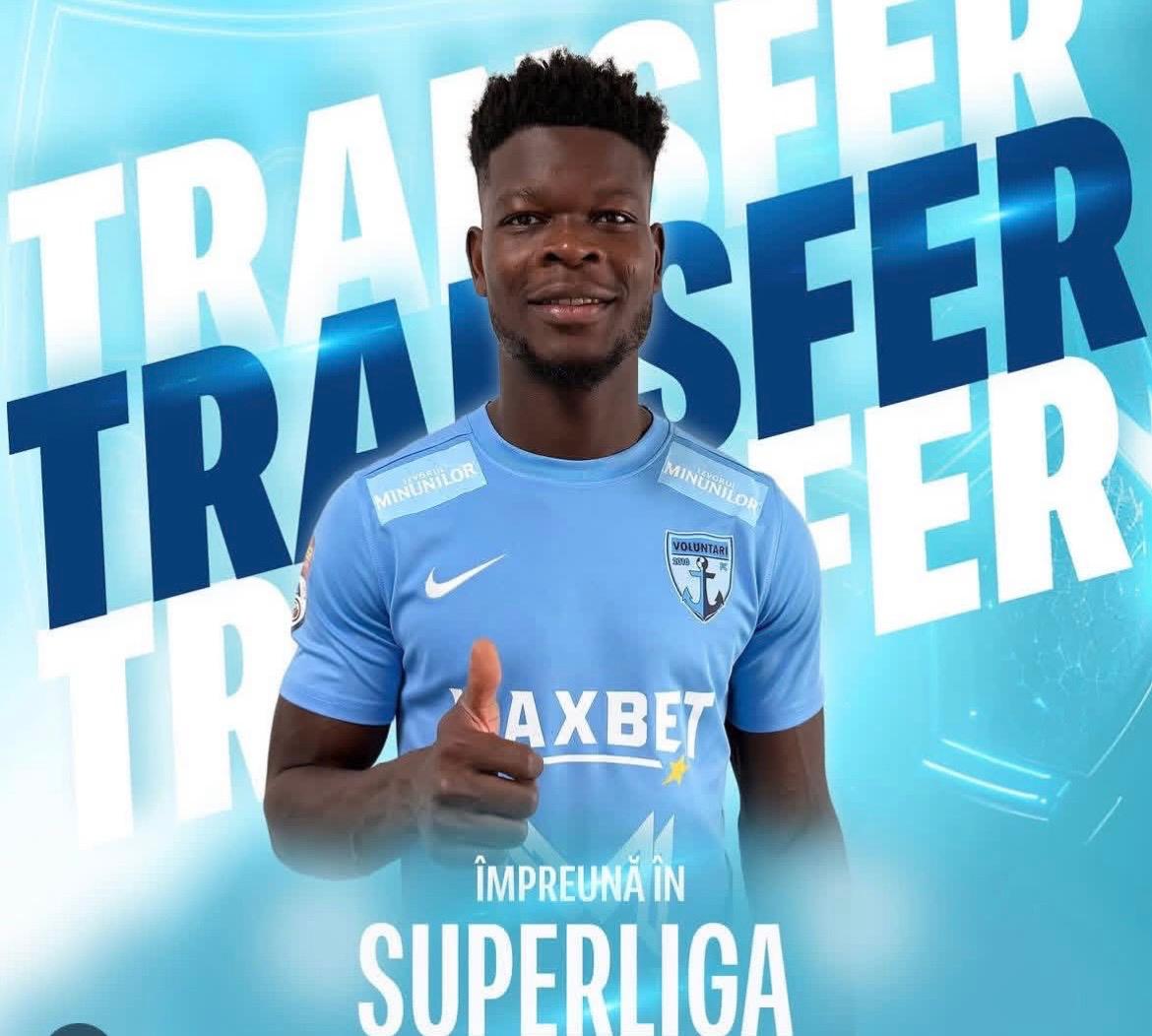 Homme en maillot de football bleu clair fait un pouce levé devant un fond marqué TRANSFER et SUPERLIGA